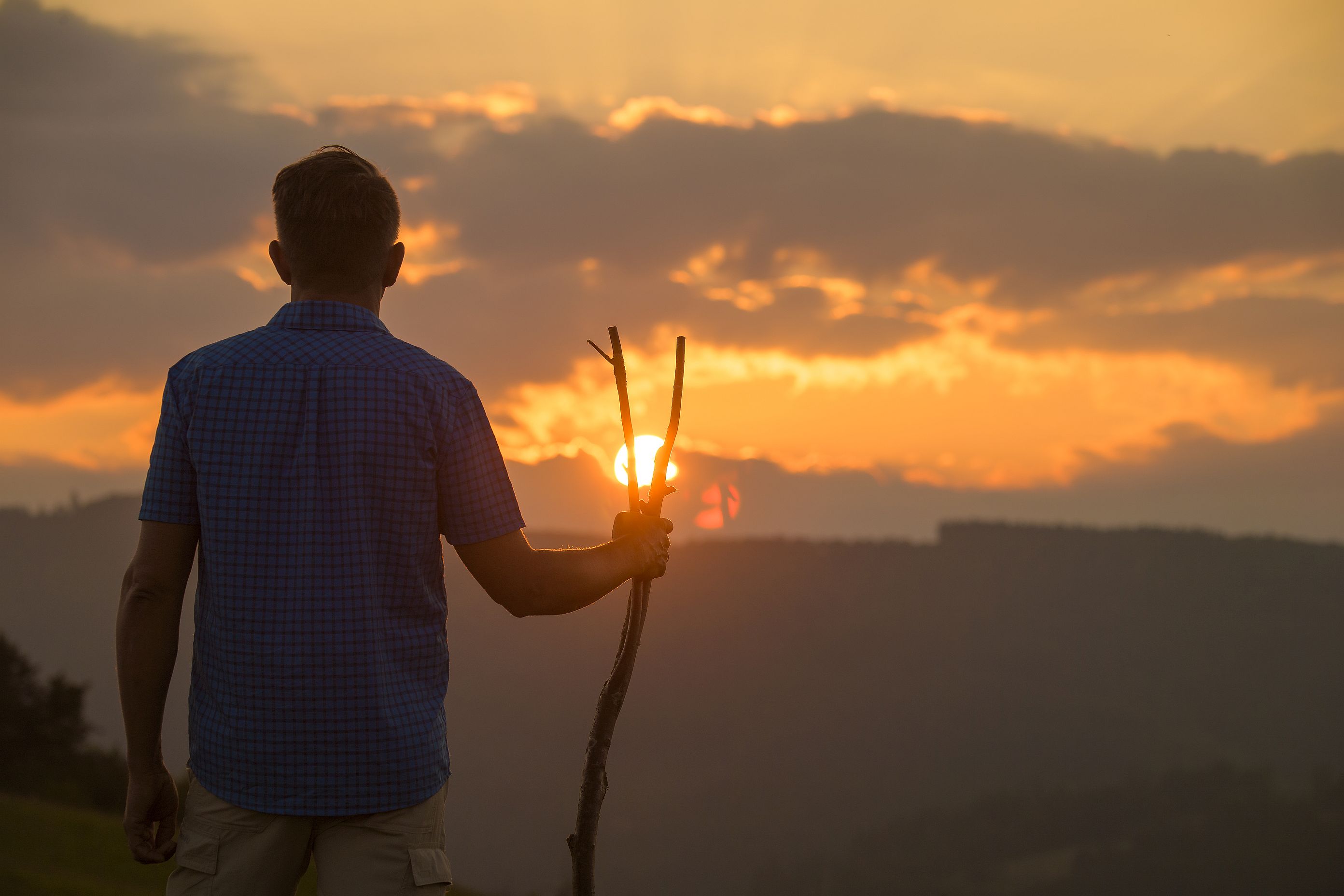 Mann mit Wanderstab bei Sonnenuntergang auf dem Upländer Besinnungsweg