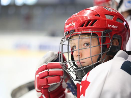 Junge im Eishockeydress mit Helm 