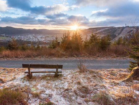 Blick auf Willingen mit einer Sitzbank bei Sonnenaufgang und Raureif 