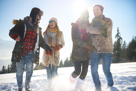 Gruppe junger Leute wandert durch den Schnee bei Sonnenschein