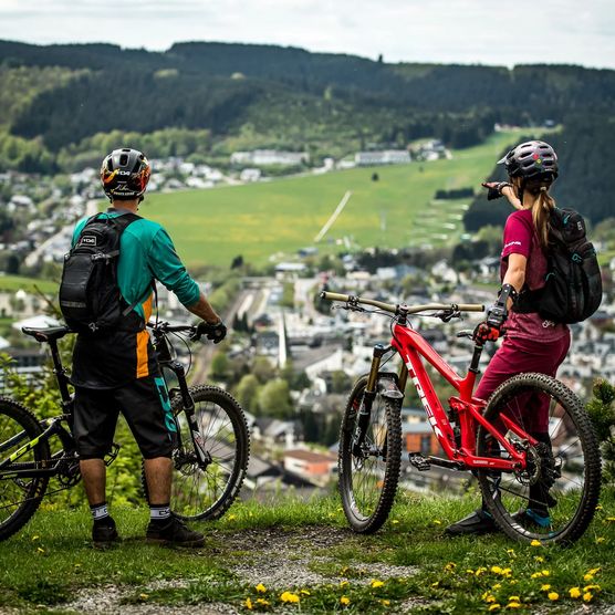 2 Mountainbiker stehen mit ihren Bikes auf dem Orenberg und schauen auf Willingen