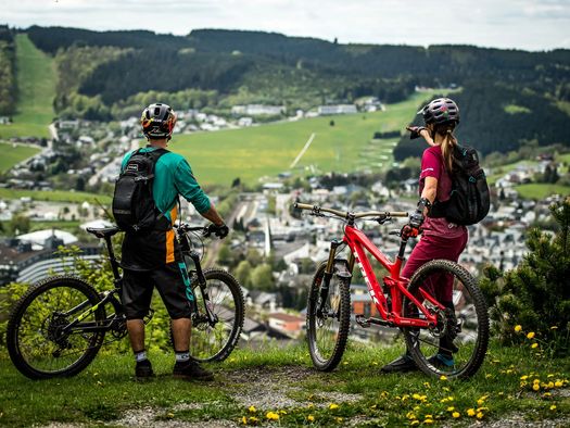 2 Mountainbiker stehen mit ihren Bikes auf dem Orenberg und schauen auf Willingen