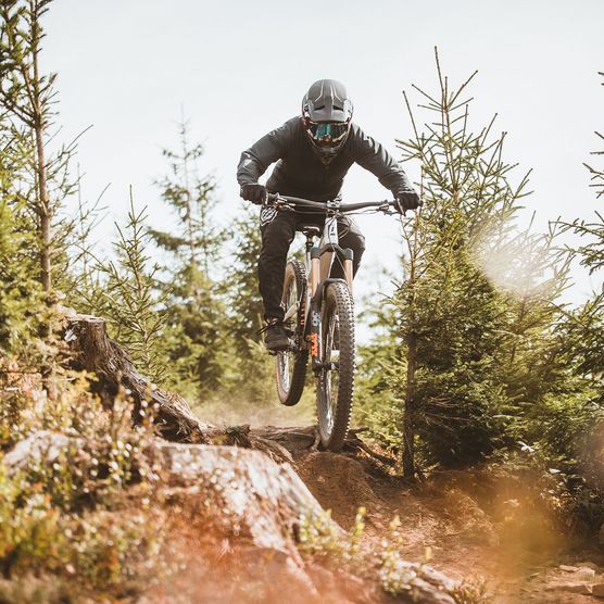 Ein Biker fährt über eine Baumwurzel auf dem Enduro-Trail im MTB Zone Bikepark