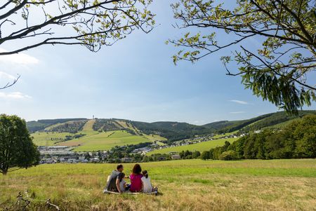 Familie sitzt auf einer Wiese in Willingen und blickt auf den Ettelsberg 