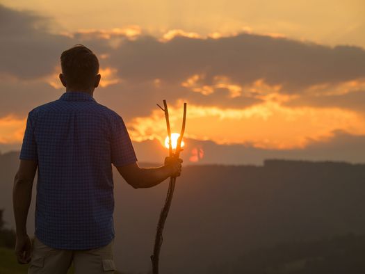 Mann mit Wanderstab bei Sonnenuntergang auf dem Upländer Besinnungsweg