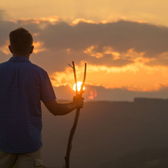 Mann mit Wanderstab bei Sonnenuntergang auf dem Upländer Besinnungsweg