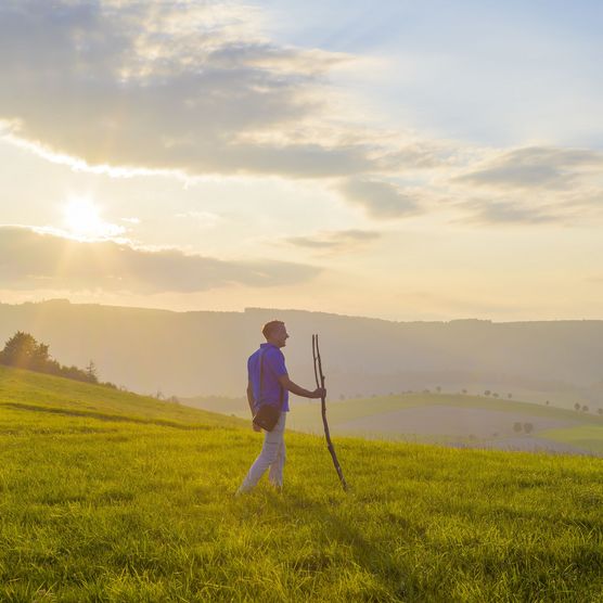 Mann mit Pilgerstab im Abendlicht auf dem Upländer Besinnungsweg