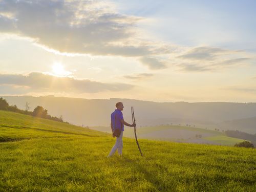 Mann mit Pilgerstab im Abendlicht auf dem Upländer Besinnungsweg