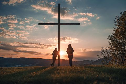 Wanderpaar beim Gipfelkreuz auf dem Orenberg bei Sonnenuntergang