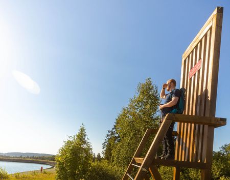 Wanderer steht auf dem großen Stuhl auf dem Ettelsberg und schaut in die Ferne 