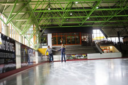 Paar auf der Eisfläche in der Eissporthalle Willingen, im Hintergrund Café Treffpunkt