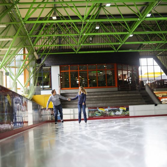 Paar auf der Eisfläche in der Eissporthalle Willingen, im Hintergrund Café Treffpunkt