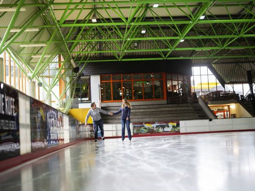 Paar auf der Eisfläche in der Eissporthalle Willingen, im Hintergrund Café Treffpunkt